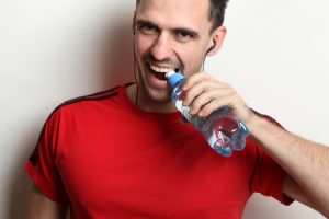 Man Opening Bottle of Water with Teeth